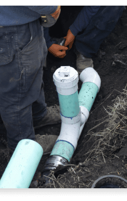 Plumber repairing a sewer line with PVC pipes, showcasing emergency drain service expertise by Hunt's Services.