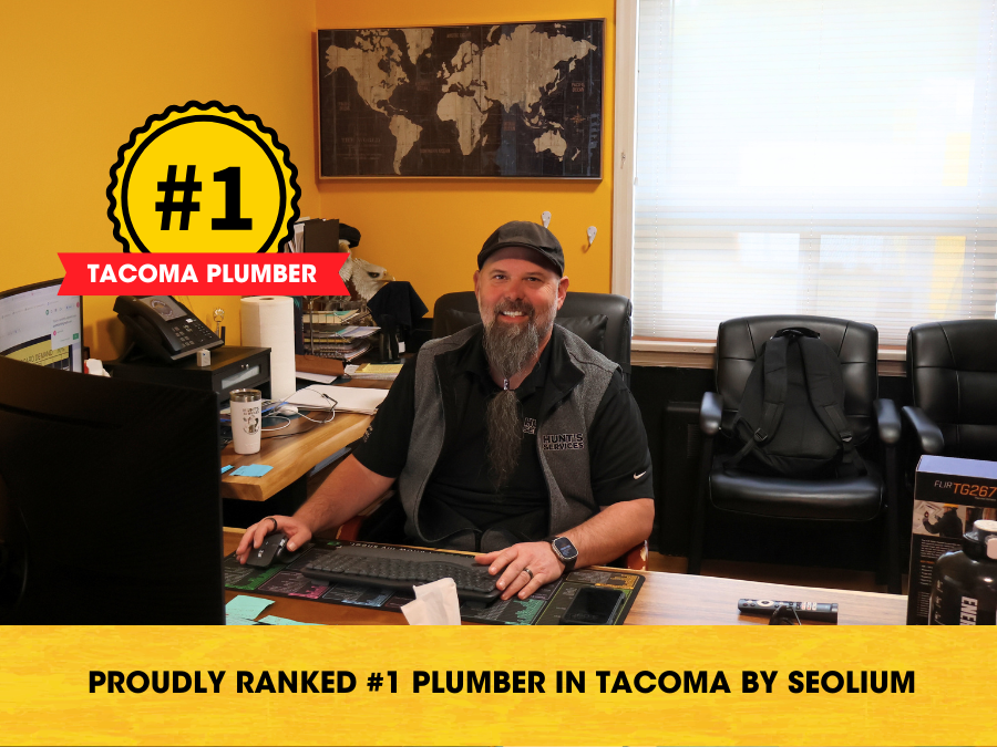#1 Tacoma plumber at Hunt's Services, proudly ranked by Seolium, sitting at desk in office with tools and equipment visible.
