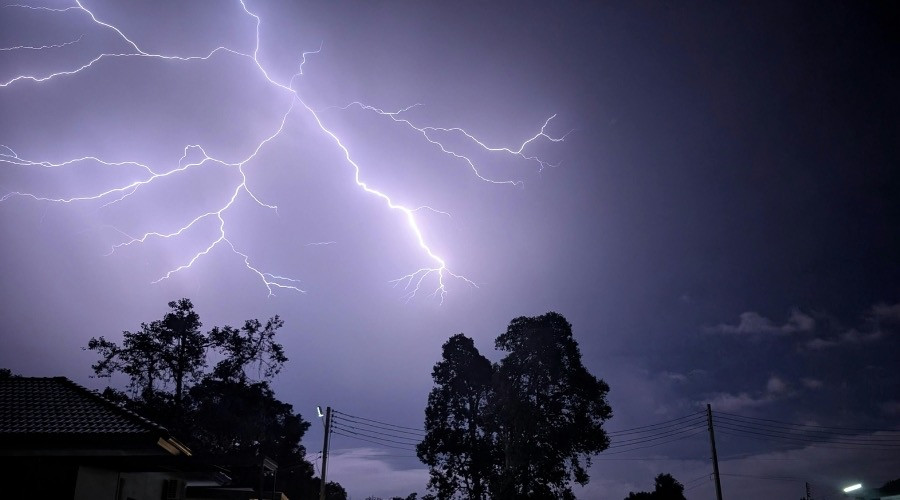 Lightning striking during a storm, illustrating the dangers of power surges and the need for whole-home surge protectors.